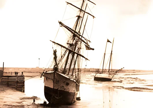 After AI enhancement (2x upscale): small 1908 photo of sailing ships at low tide on a river